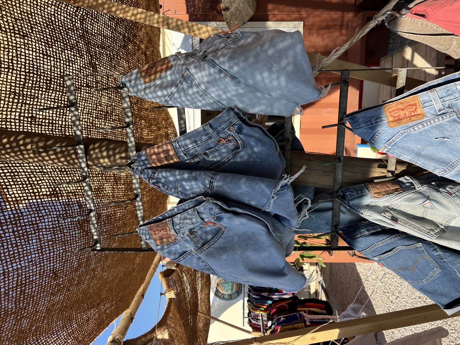 Gros plan sur des jeans Levi's vintage suspendus, étiquettes cuir, lumière tamisée